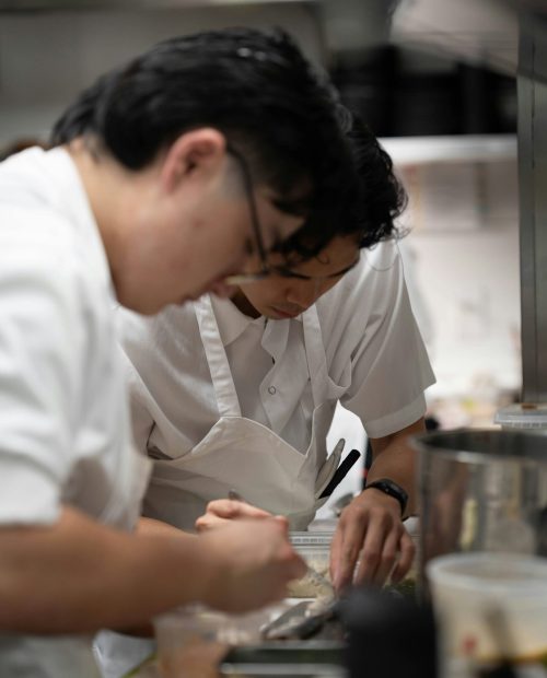 To restaurantmedarbejdere samarbejder om anretning ved bord