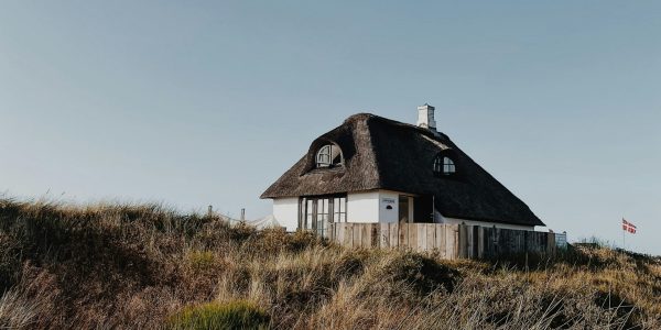 Stråtækt hus i klitlandskab under blå himmel